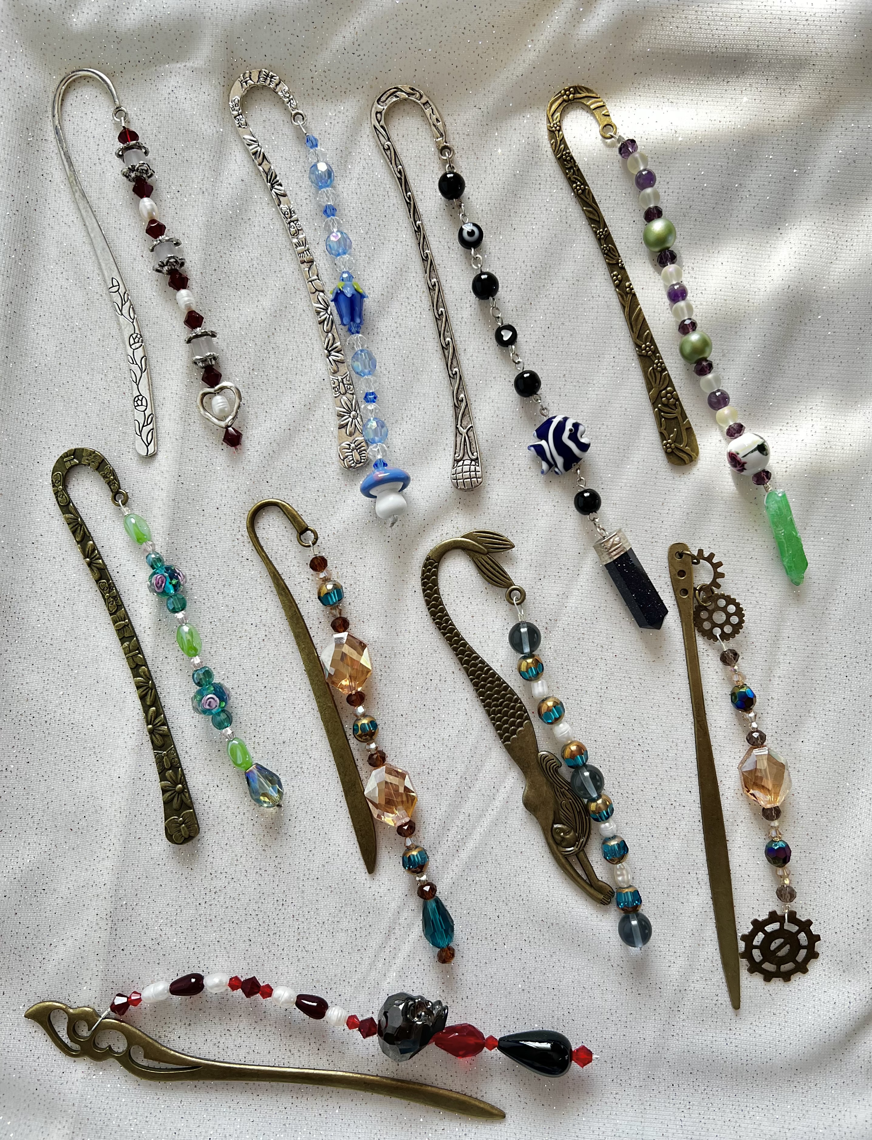 Nine handmade beaded bookmarks laid out on white linen